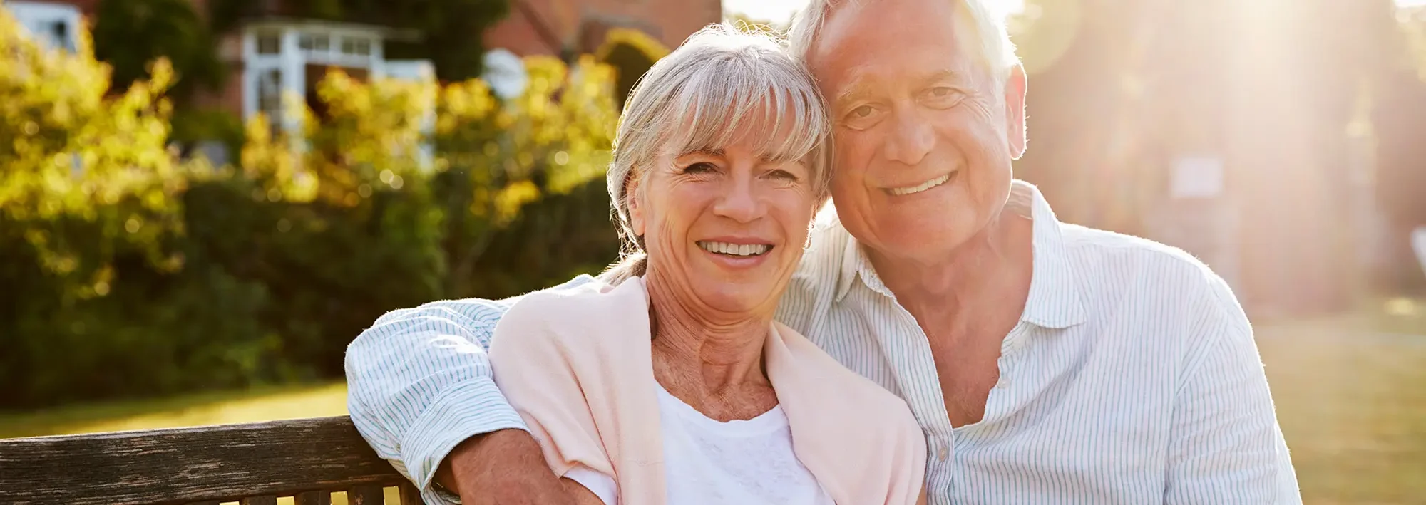 An older couple hugging and looking at the camera