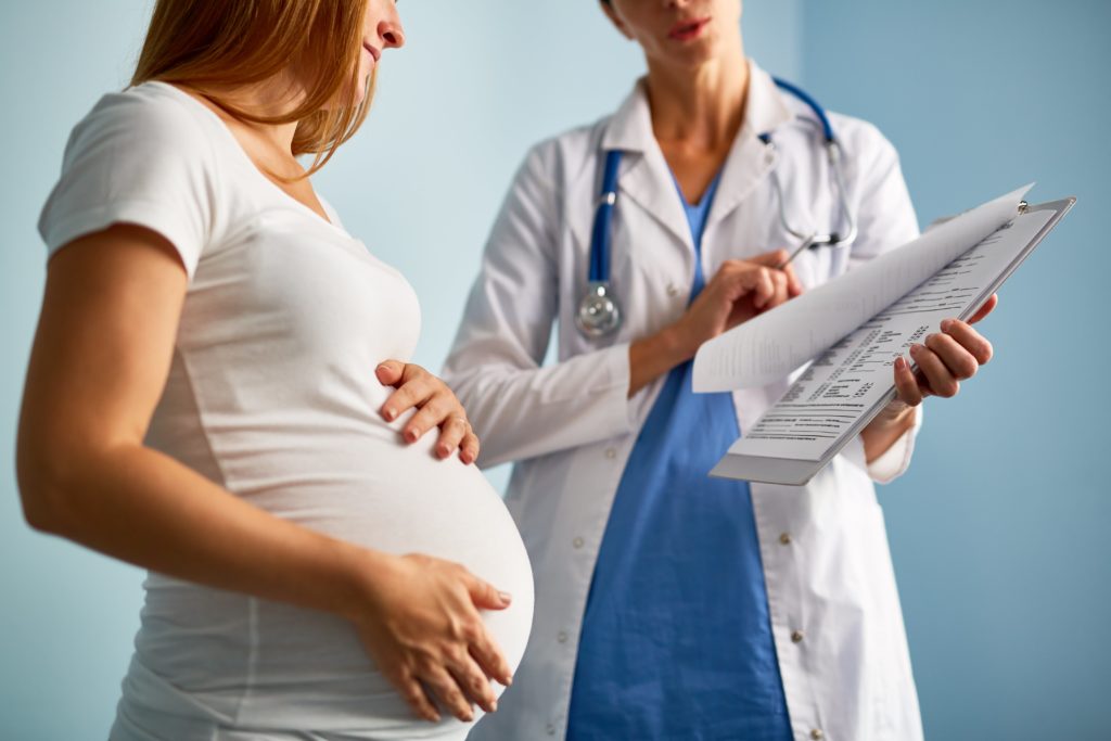 Doctor Presenting Paperwork to Pregnant Woman