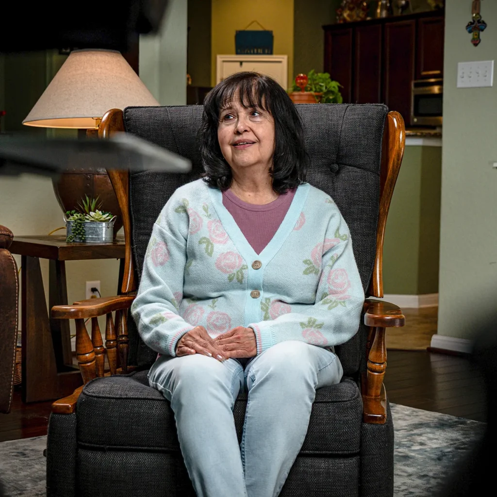 Linda sits in a chair in her living room